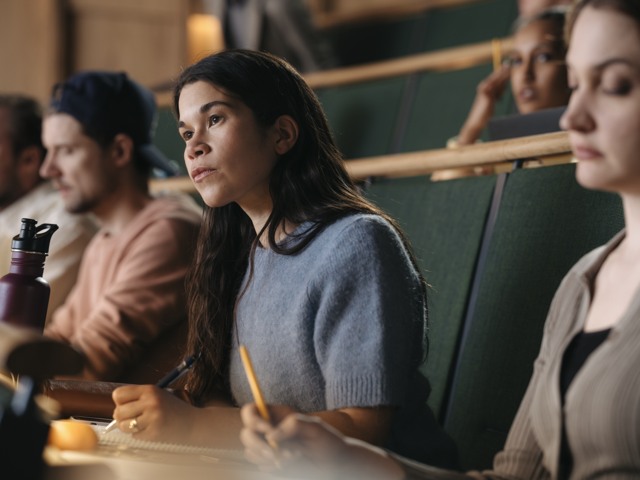 Kvinnlig student under föreläsning i aula vid högskola Högskola - porträtt