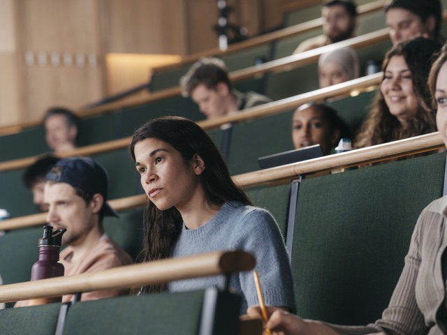 Kvinnlig student under föreläsning i aula vid högskola Högskola - porträtt