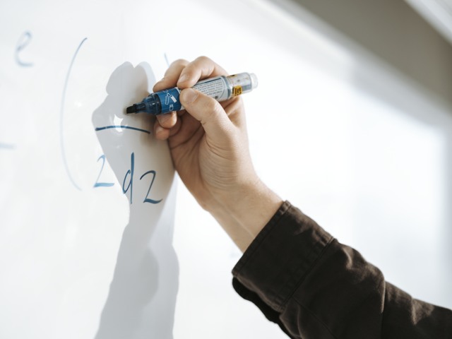 Hand med penna skriver på whiteboard under föreläsning vid högskola Högskola - detaljbild