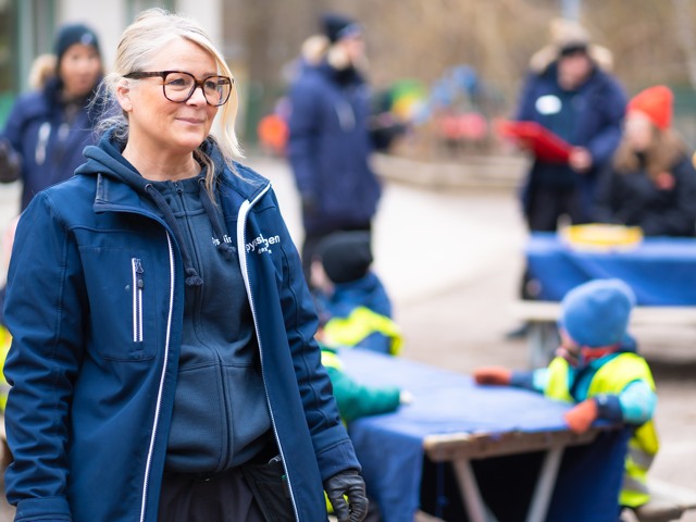 Glad förskollärare med elever utomhus Förskola - fristående