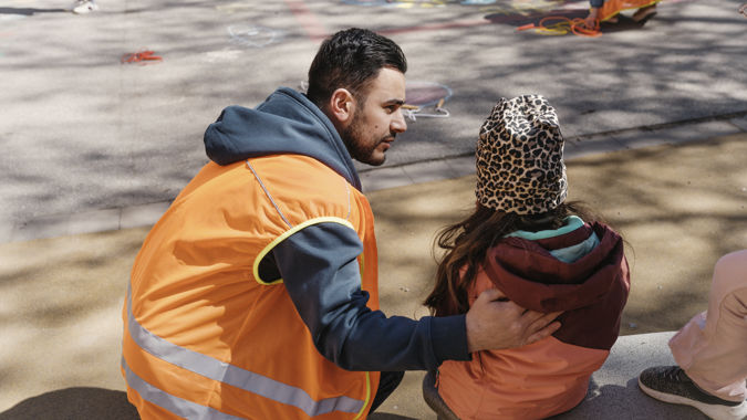 Förskollärare tröstar elev utomhus.