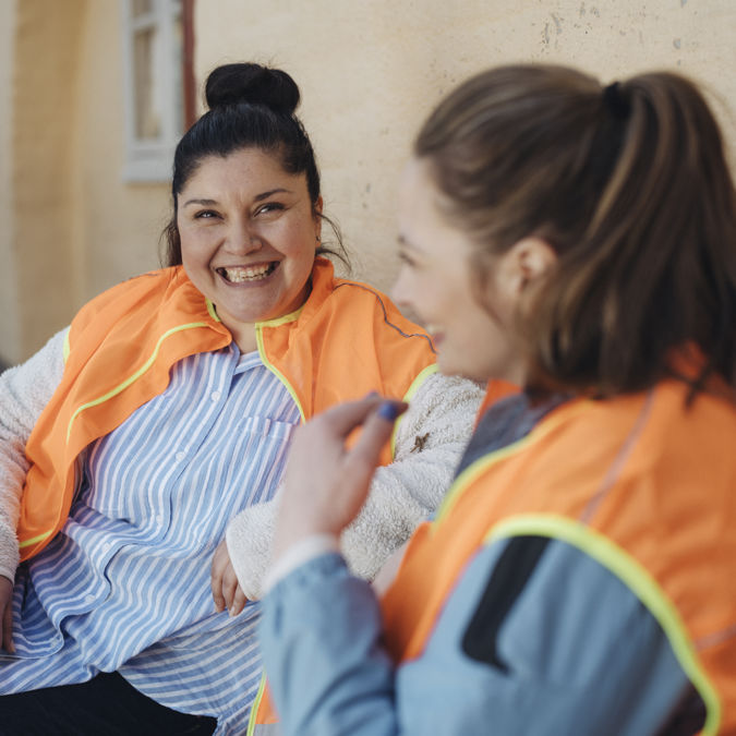 Två glada förskollärare utomhus.