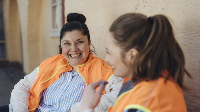 Två glada förskollärare utomhus.