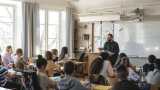 Grundskollärare med elever i ett klassrum.
