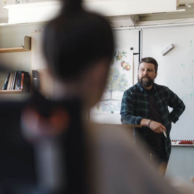 Grundskollärare med elever i ett klassrum.