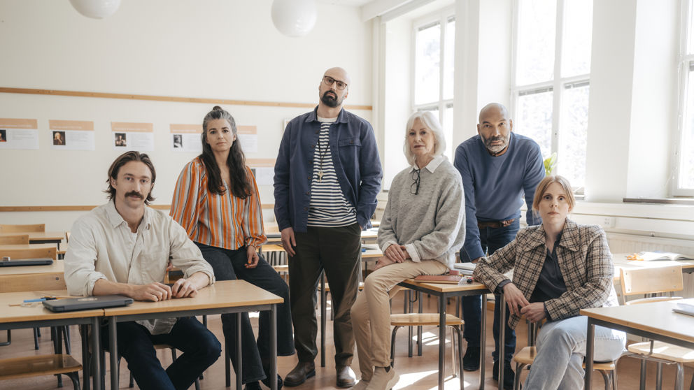 En grupp allvarliga gymnasielärare i ett klassrum.