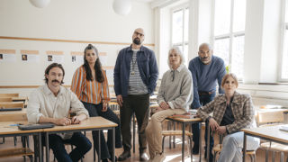 En grupp allvarliga gymnasielärare i ett klassrum.
