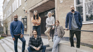 En grupp allvarliga gymnasielärare vid trappen till ingången till en skola.