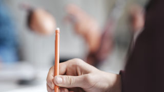 Närbild av hand med penna - skiss av hjärta under biologilektion.