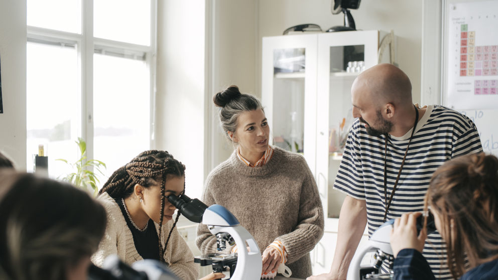 Två gymnasielärare med elever under lektion i biologi.