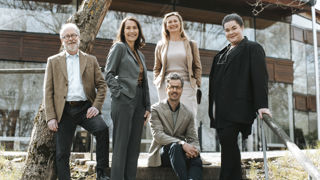 En grupp leende lärare vid högskola utomhus.