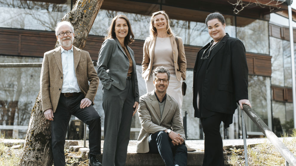 En grupp leende lärare vid högskola utomhus.