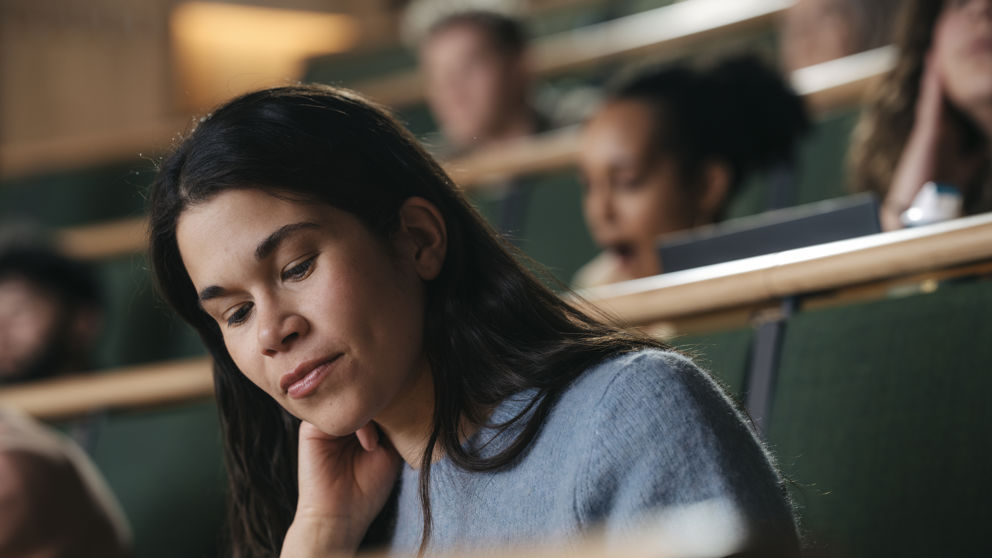Kvinnlig student under föreläsning i aula vid högskola.