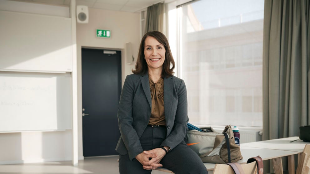 Kvinnlig leende lärare vid högskola inomhus.