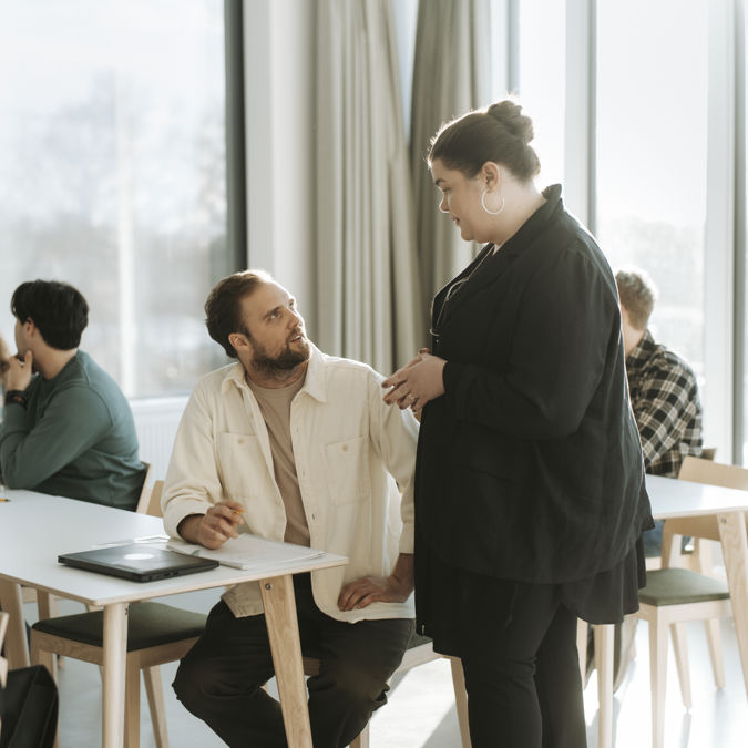 Kvinnlig lärare och studenter under föreläsning vid högskola.