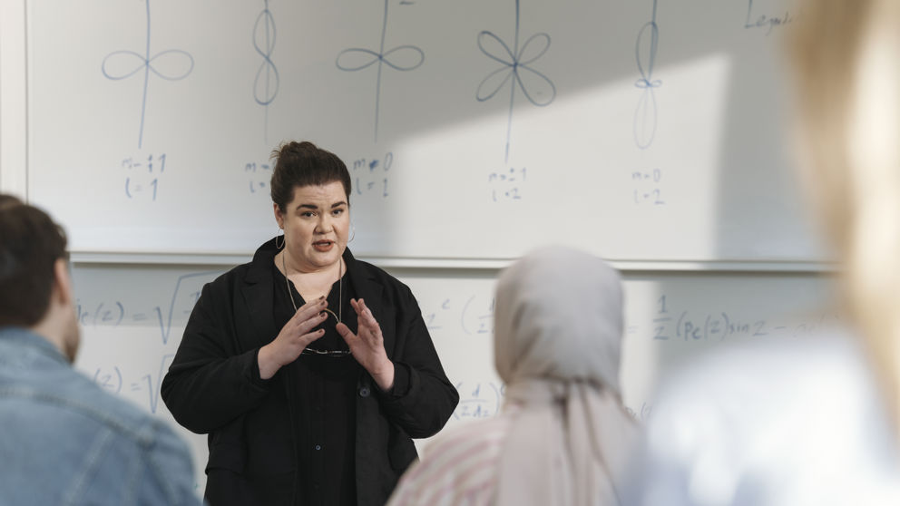 Kvinnlig lärare och studenter under föreläsning vid högskola.
