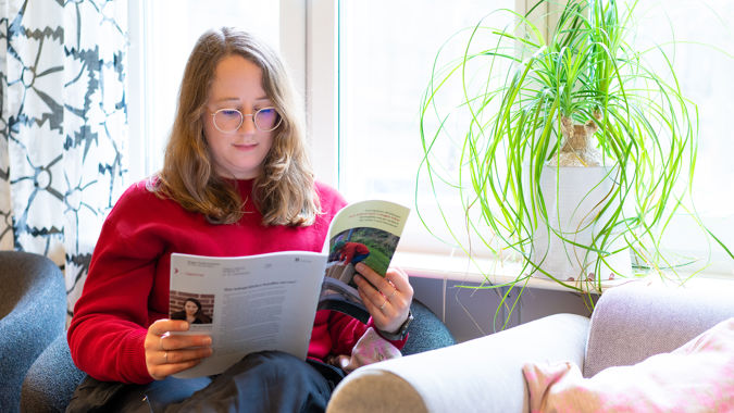 Förskollärare i soffa läser tidning iHammarbyhöjden, Stockholm.