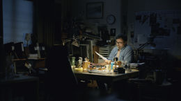 Lärare  arbetar vid skrivbord i ett mörk rum sen kvällstid.