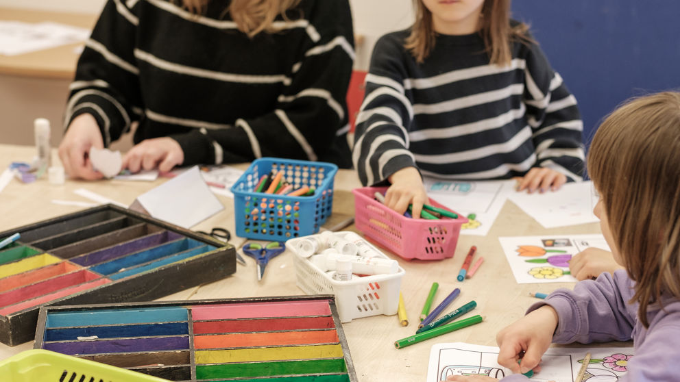 Elever man inte ser ansiktena på sitter och målar vid ett bord på Karlbergs fritidshem.