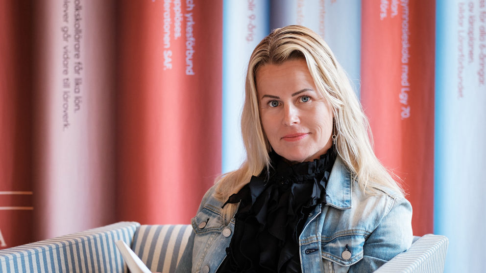 Sveriges Lärares ordförande Anna Olskog i svart tröja och blå jeansjacka läser en bok.