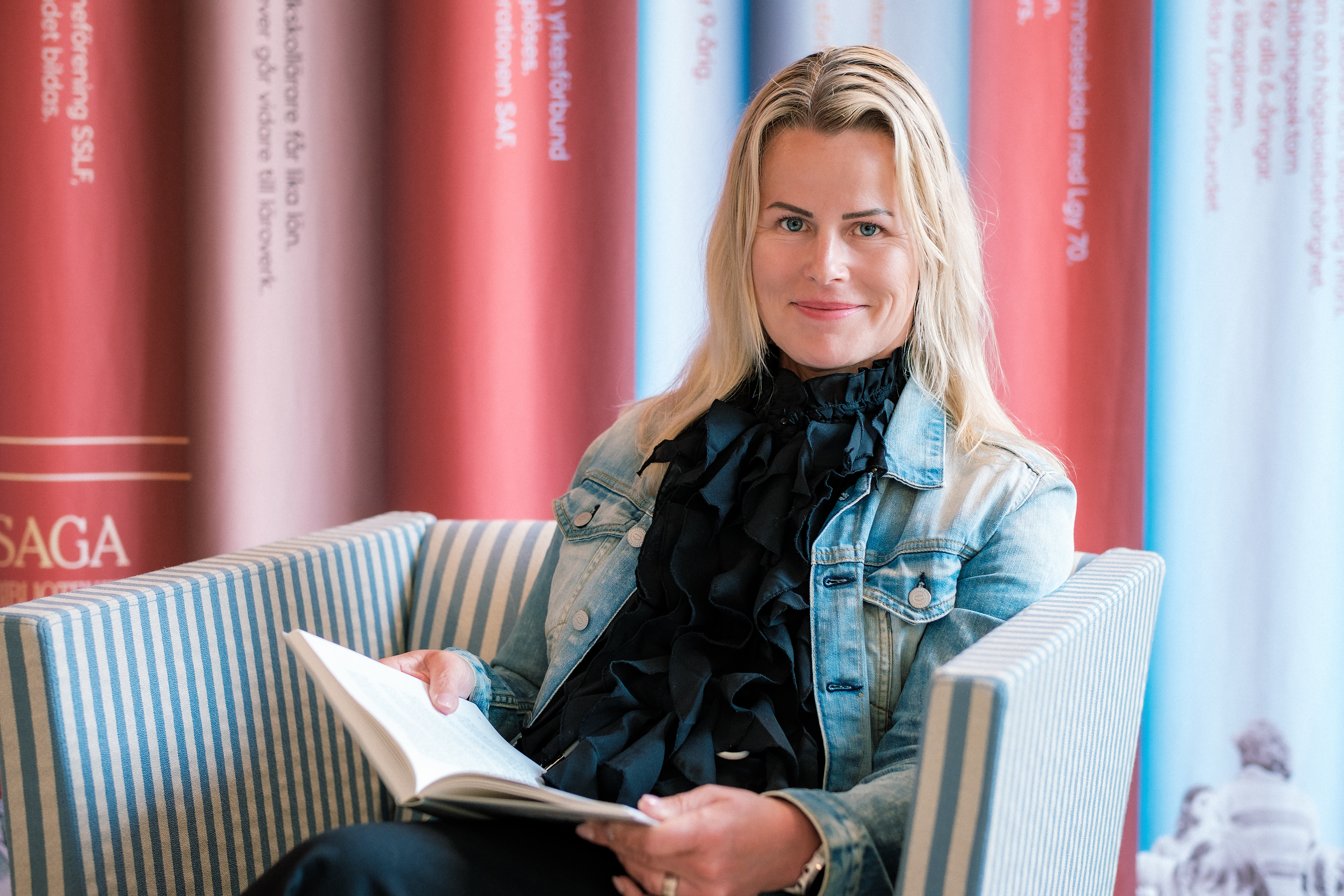 Sveriges Lärares ordförande Anna Olskog i svart tröja och blå jeansjacka läser en bok.