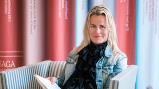 Sveriges Lärares ordförande Anna Olskog i svart tröja och blå jeansjacka läser en bok.