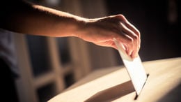 Conceptual image of a person voting, casting a ballot at a polling station, during elections.