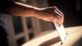 Conceptual image of a person voting, casting a ballot at a polling station, during elections.