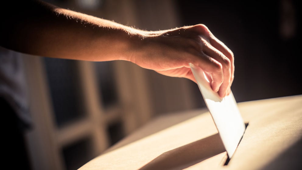 Conceptual image of a person voting, casting a ballot at a polling station, during elections.