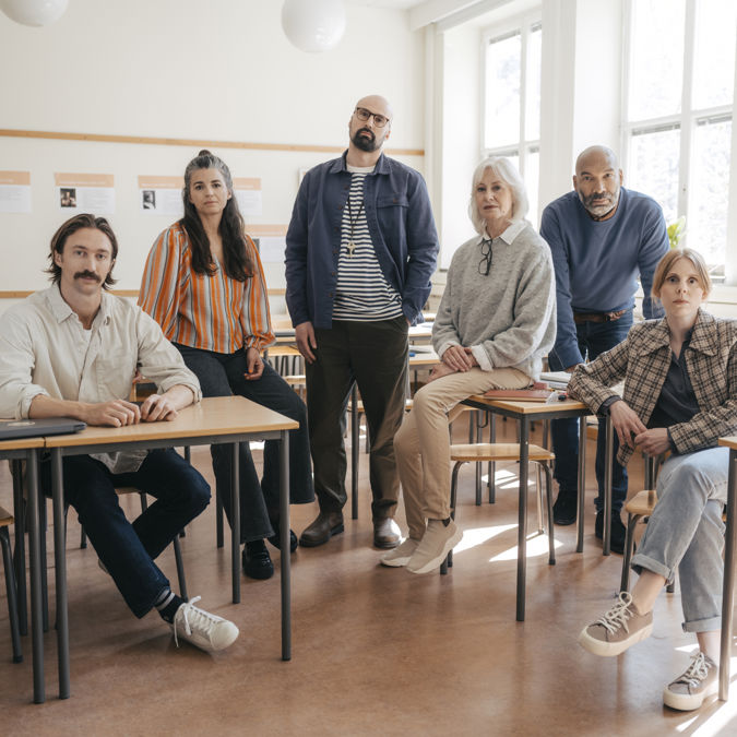 En grupp allvarliga gymnasielärare i ett klassrum.
