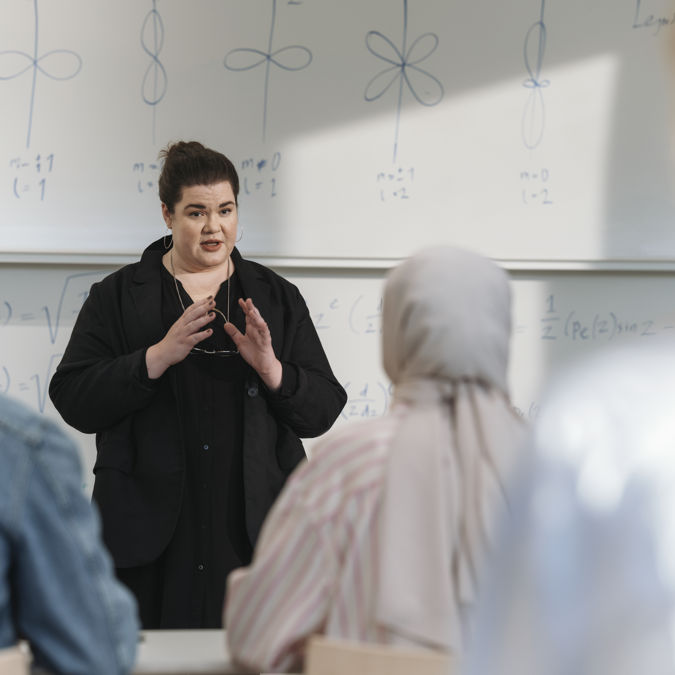 Kvinnlig lärare och studenter under föreläsning vid högskola.