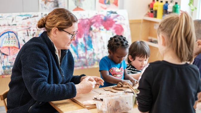 Förskollärare och barn med modellera.
